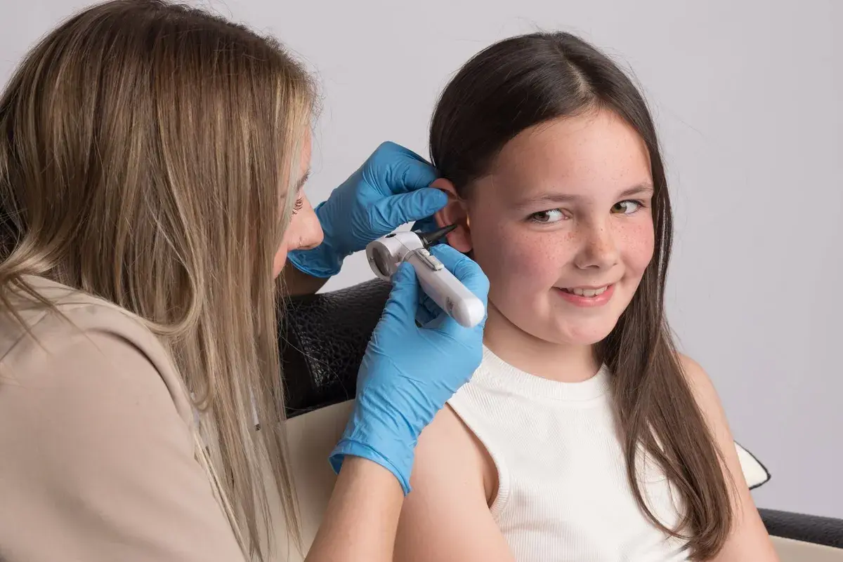 Deanna gently checking a young girl’s ear, the child smiling and relaxed