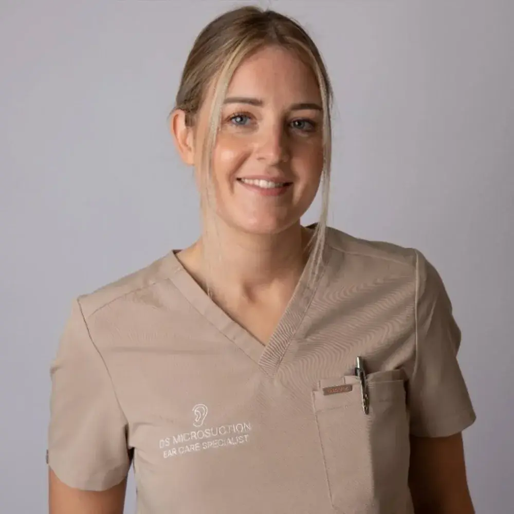 Deanna Spiby, owner of DS Microsuction, smiling in her branded ear-care uniform